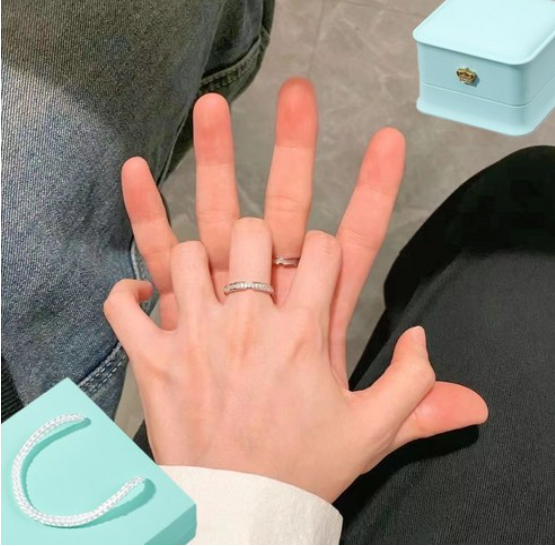 Couple ring set worn on fingers, showcasing sterling silver rings with a jewelry box in the background.